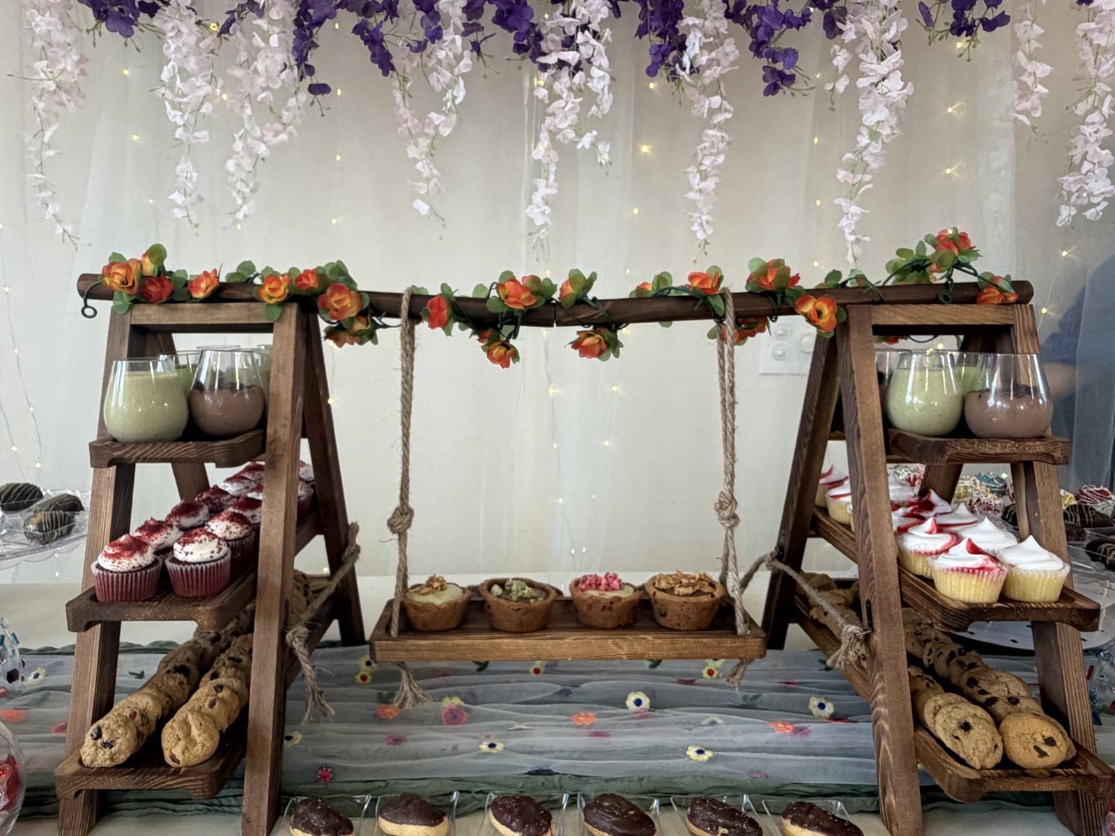 Wooden ladder and hanging swing centerpiece trimmed with orange roses, holding cookie cups, cupcakes and dessert shooters